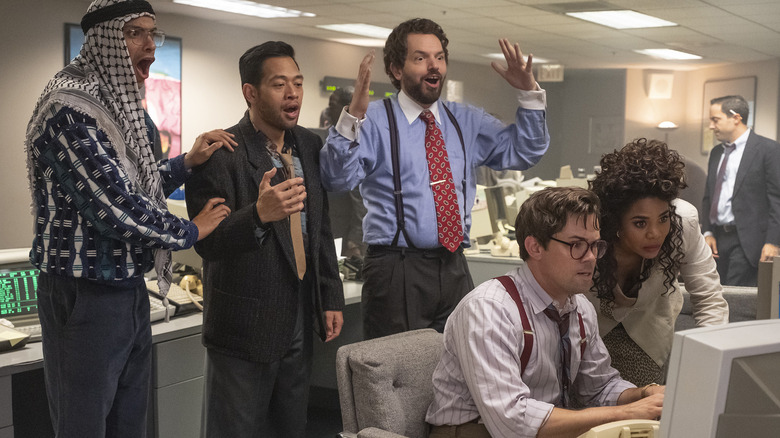 The characters gather around a computer