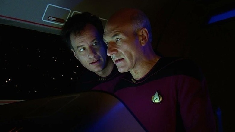 Q (John de Lancie) hangs over the shoulder of Jean-Luc Picard (Patrick Stewart) in a shuttlecraft in Star Trek: The Next Generation