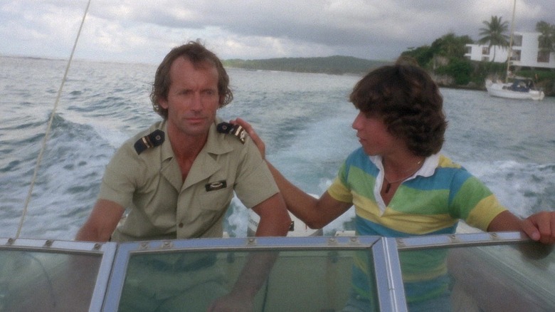 Lance Henriksen as Police Chief Steve Kimbrough drives a boat with a kid in Piranha II: The Spawning