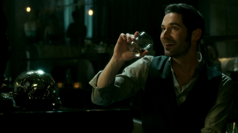 Lucifer (Tom Ellis) drinking with a smile in Lucifer