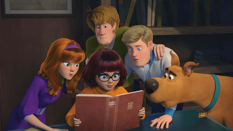 The Mystery Gang crowd around a book in Scoob!