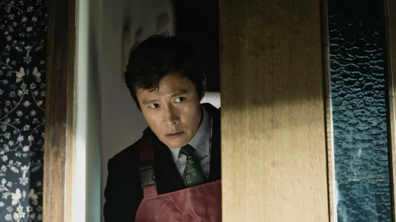 Yoo Man-su (Lee Byung-hun) peeking behind door in No Other Choice