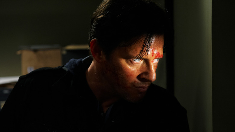 Costas Mandylor as Hoffman peeking through a window with blood on his face in Saw 3D