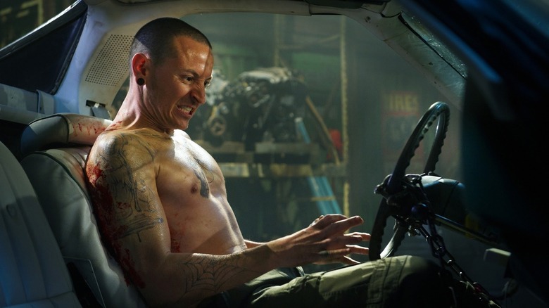 Chester Bennington as Evan chained to a car in Saw 3D
