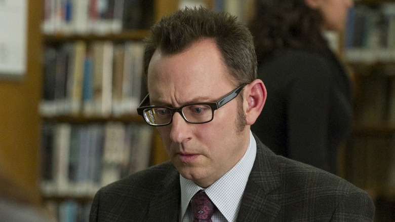 Harold Finch working on a laptop with concern in his eyes in Person of Interest