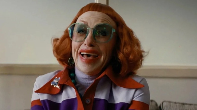Gladys smiling with green glasses in Marcus' office on Weapons