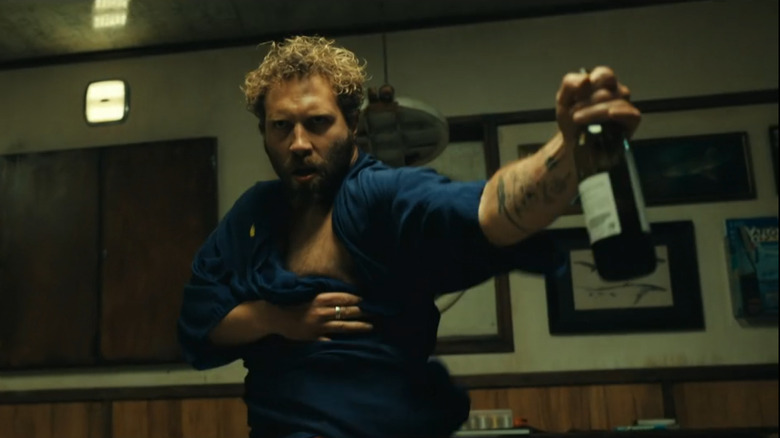 Jai Courtney as Tucker in Dangerous Animals, dancing in his bathrobe with an alcoholic beverage