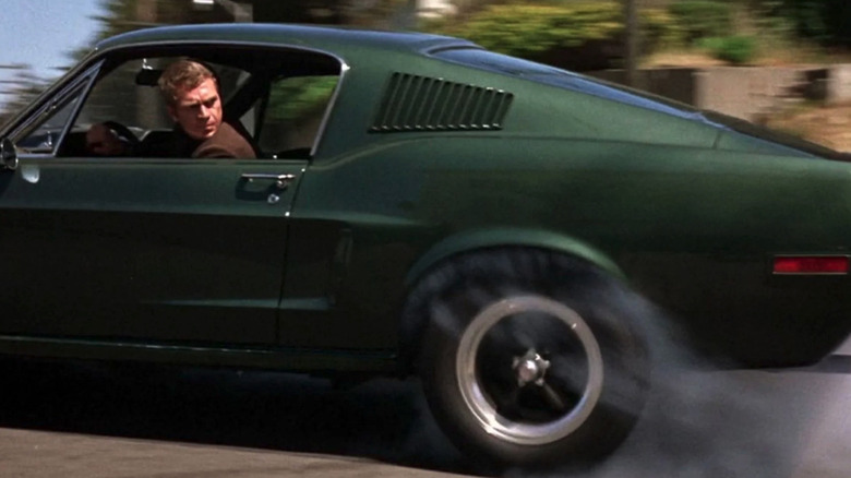 Frank Bullitt (Steve McQueen) looks back while driving a green Ford Mustang in Bullitt