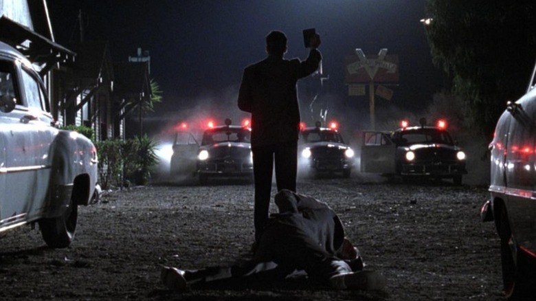 Ed Exley (Guy Pearce) holds up his badge to approaching police cars over a body in L.A. Confidential