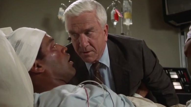 Frank Drebin (Leslie Nielsen) speaks to a bedridden Nordberg (O.J. Simpson) in The Naked Gun