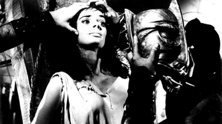 A witch about to have an iron mask nailed onto her face