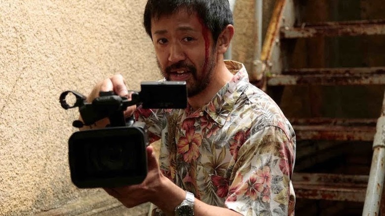 Bloody man holding film camera