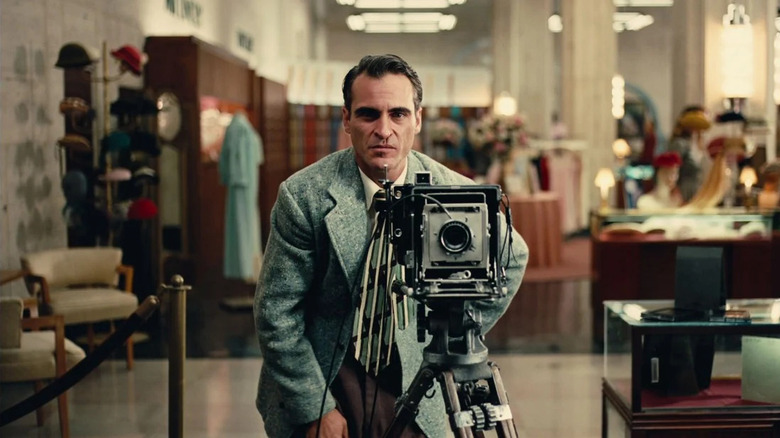 Freddie Quell (Joaquin Phoenix) stands behind a camera in a department store in The Master (2012)