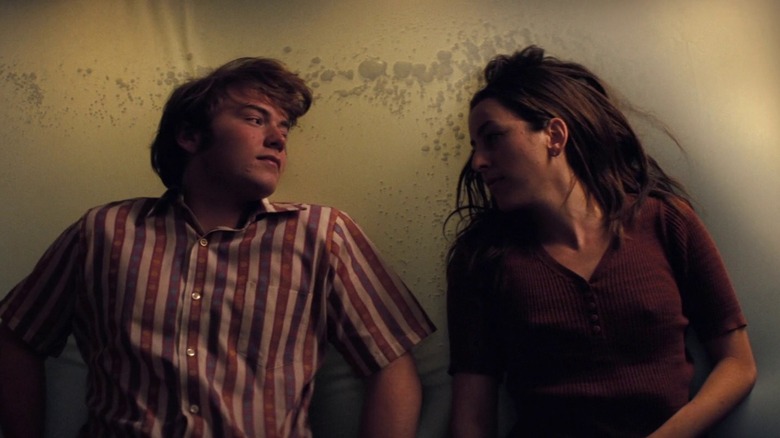 Alana Haim as Alana Kane and Cooper Hoffman as Gary Valentine in Licorice Pizza, laying on a waterbed and looking at each other.