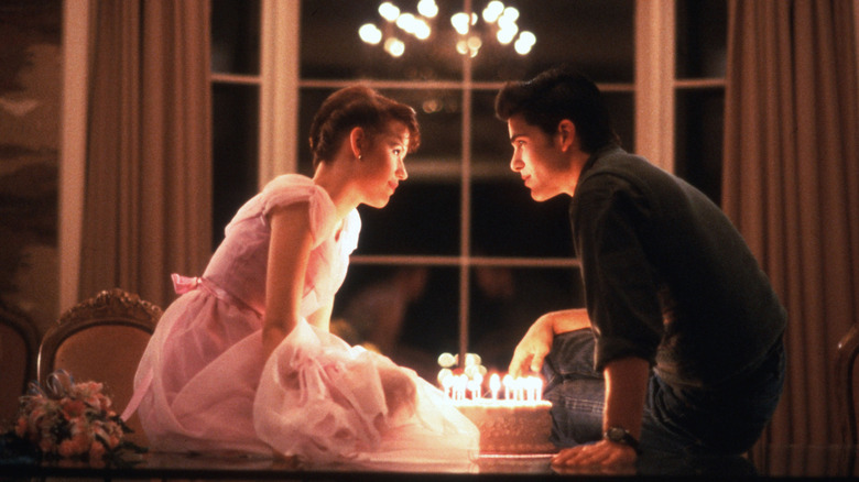 Molly Ringwald and Michael Schoeffling as Sam and Jake around a birthday cake with lit candles in Sixteen Candles