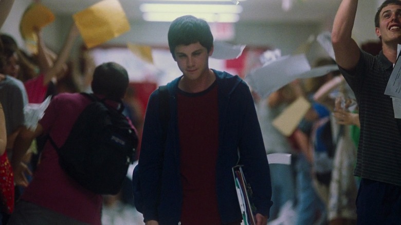 Logan Lerman as Charlie in The Perks of Being A Wallflower, walking through a high school hallway where papers are being thrown in the air.