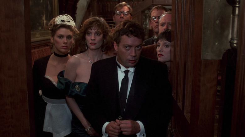 Tim Curry as Wadsworth, Lesley Ann Warren as Miss Scarlet, Madeline Kahn as Mrs. White, Christopher Lloyd as Professor Plum, Martin Mull as Colonel Mustard, Michael McKean as Mr. Green, and Colleen Camp as Yvette standing at the door in Clue