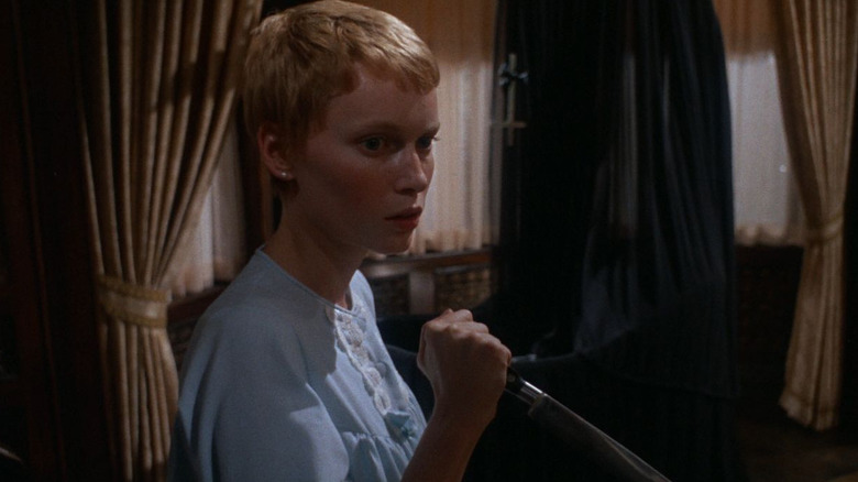Rosemary (Mia Farrow) looks cautiously with a knife in hand in Rosemary's Baby