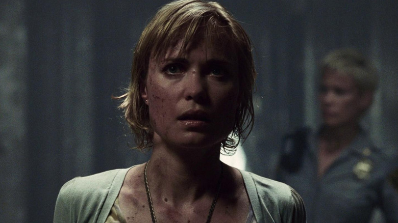 Rose (Radha Mitchell) looks scared in a dimly lit hall in Silent Hill