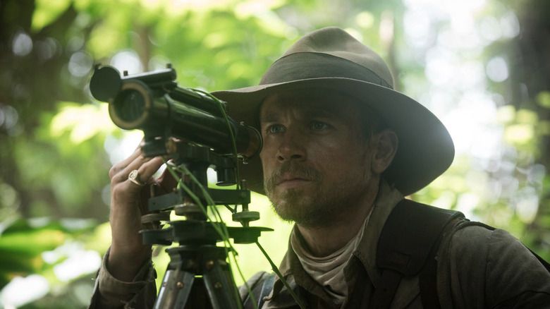 Charlie Hunnam as Percy Fawcett looking through a telescope in the jungle in The Lost City of Z