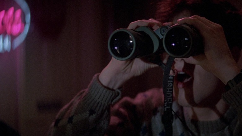 Charley (William Ragsdale) peering out his window with binoculars in Fright Night