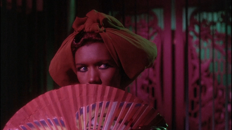 Katrina (Grace Jones) holding fan over face in Vamp
