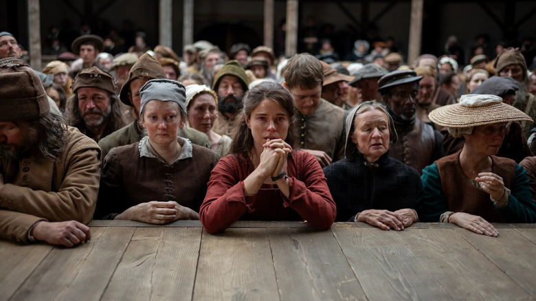 Agnes watching Hamlet crying with her hands clasped in the audience in Hamnet