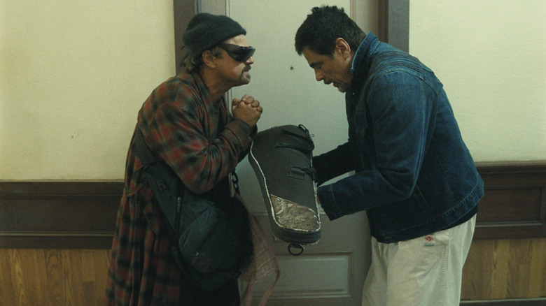 Leonardo DiCaprio as Bob Ferguson and Benicio del Toro as Sensei St. Carlos standing in a hallway in One Battle After Another