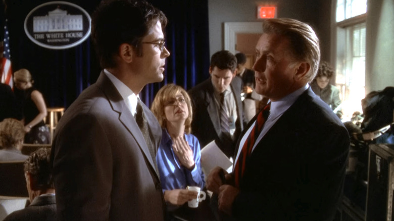 Rob Lowe as Sam Seaborn talking to Martin Sheen as President Jed Bartlet in front of Allison Janney as C. J. Cregg who is sitting down in the White House press room in The West Wing
