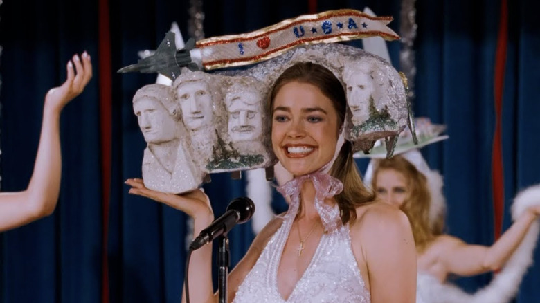 Denise Richards Becky Ann Leeman wearing her Mount Rushmore headpiece and smiling onstage in Drop Dead Gorgeous