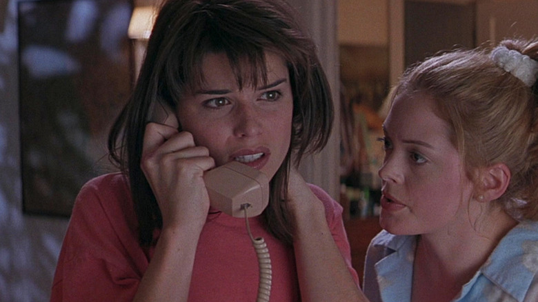 Sidney (Neve Campbell) looks scared on the phone as Tatum (Rose McGowan) watches in Scream (1996)