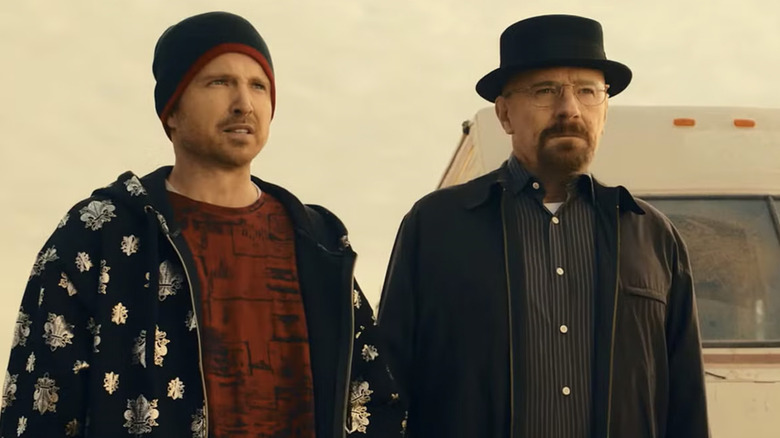 Aaron Paul as Jesse Pinkman wearing a beanie and Brian Cranston wearing his Heisenberg hat while standing in fron of an RV outside in Breaking Bad