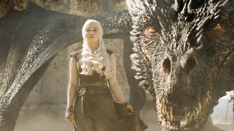 Emilia Clarke as Daenerys Targaryen standind in front of Drogon while they both look fierce and angry in Game of Thrones