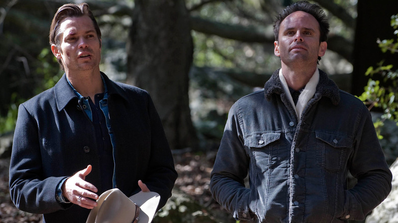 Timothy Olyphant as Deputy U.S. Marshal Raylan Givens with a cut face holding a cowbow hat and Walton Goggins as Boyd Crowder with his hands in his pockets standing outside in Justified