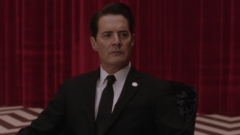 Kyle MacLachlan as Agent Dale Cooper wearing his FBI suit and looking serious while sitting in the Black Lodge in Twin Peaks: The Return