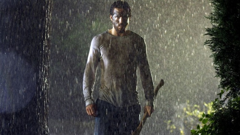 Ryan Reynolds as George Lutz holding an ax outside in the rain in The Amityville Horror (2005)