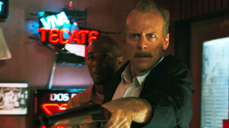 Bruce Willis' Jake Mosley aims a gun as he stands in front of Mos Def's Eddie Bunker in 16 Blocks