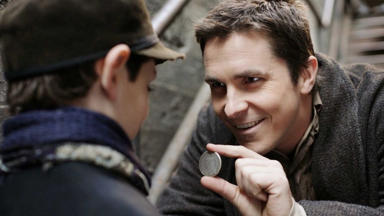Christian Bale as Alfred Borden showing a coin to a young boy in The Prestige