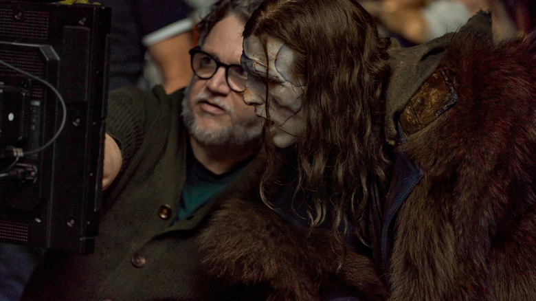 Director Guillermo del Toro points to a screen next to Jacob Elordi as the monster in a behind-the-scenes photo from the set of Frankenstein