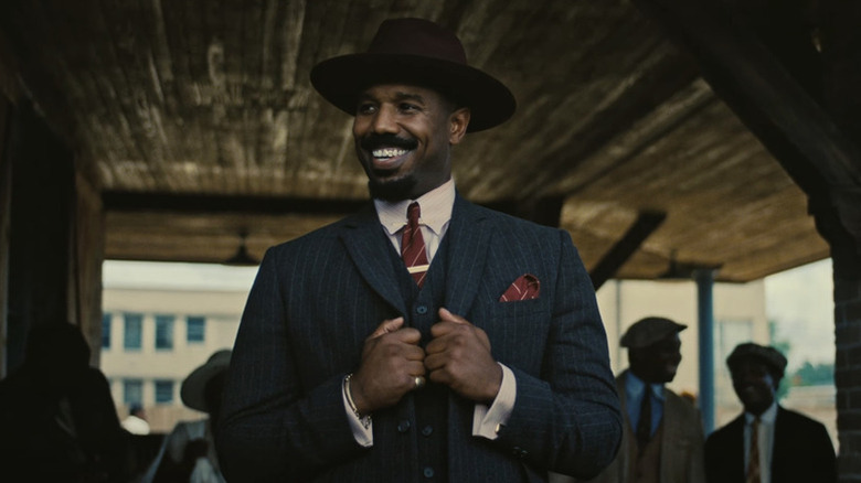 Stack fixing his suit and smiling at the train station in Sinners