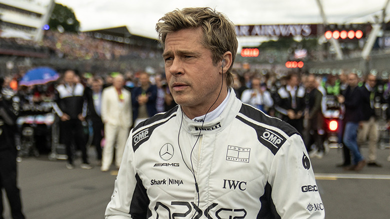 Brad Pitt as Sonny Hayes, walking through a race with headphones in in F1