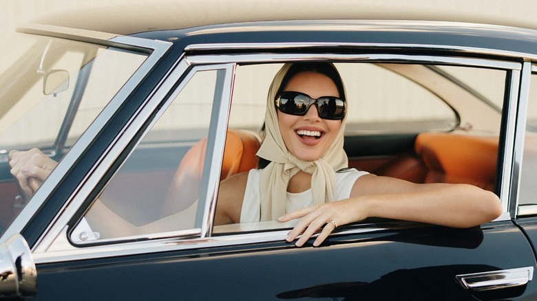 Kendall Jenner smiling in a car wearing sunglasses