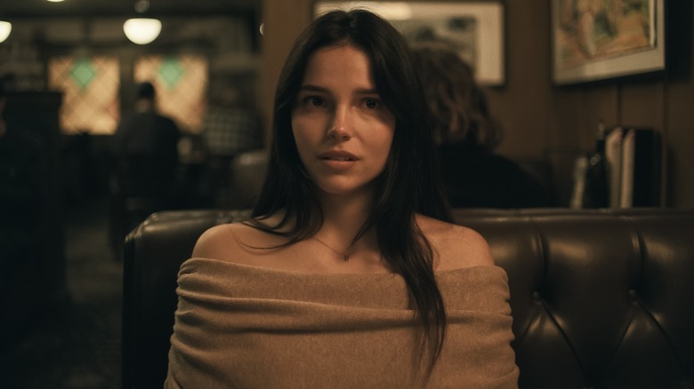 Nikki looking apprehensive in a restaurant booth in Obsession