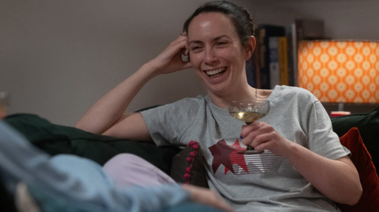 Amy holding a glass of wine and laughing in Tender Loving Care