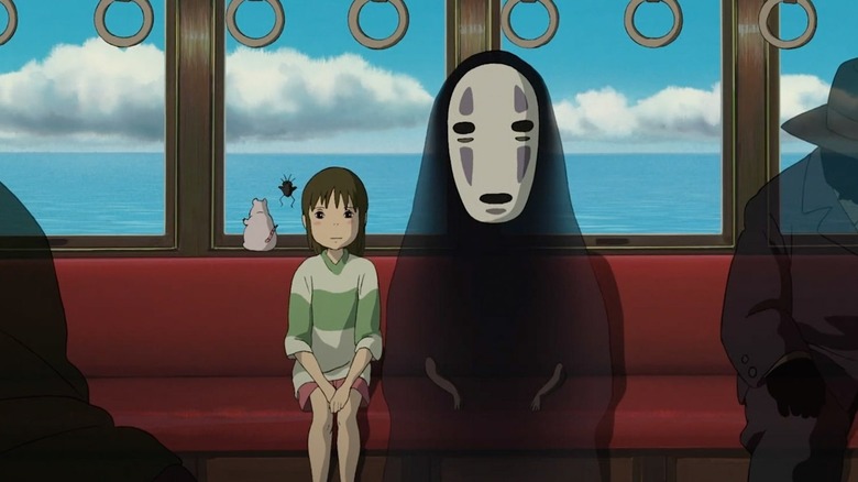 Chihiro Ogino (Rumi Hiiragi) sits on a train bench next to No-Face (Akio Nakamura) in Spirited Away