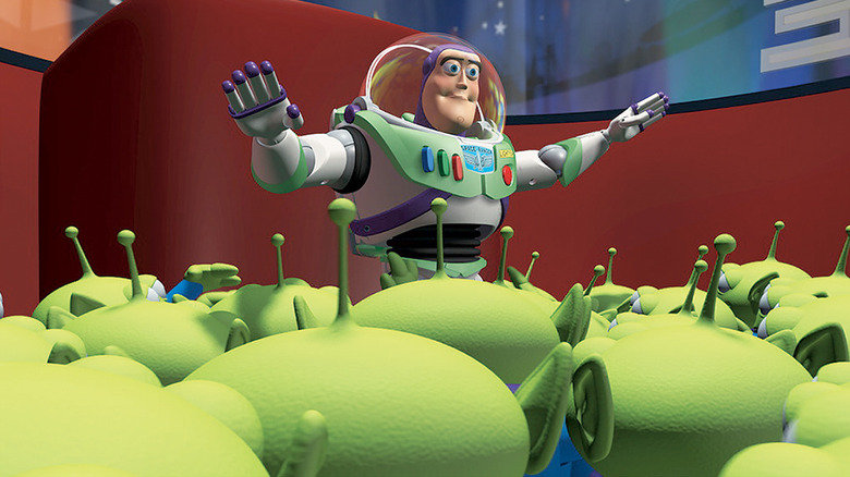 Buzz Lightyear (Tim Allen) stands with his hands outstretched over green aliens in Toy Story
