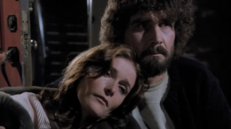 Margot Kidder's Kathy Lutz leaning her head on James Brolin's George Lutz's should in The Amityville Horror