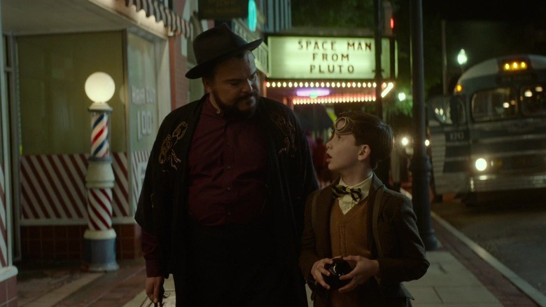 Lewis (Owen Vaccaro) and Jonathan (Jack Black) walking through town in The House With a Clock in Its Walls