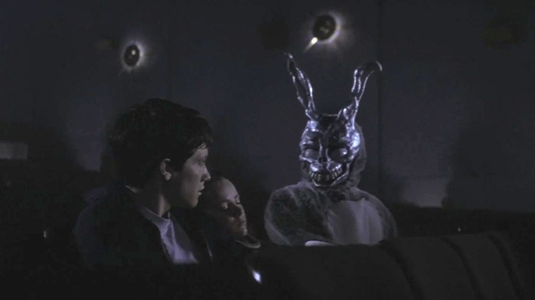 Donnie in a theater with Gretchen asleep on him, while Frank sits nearby in Donnie Darko