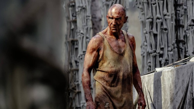 Ralph Fiennes como Dr. Kelson Bloody fica entre os pilares ósseos em 28 anos depois